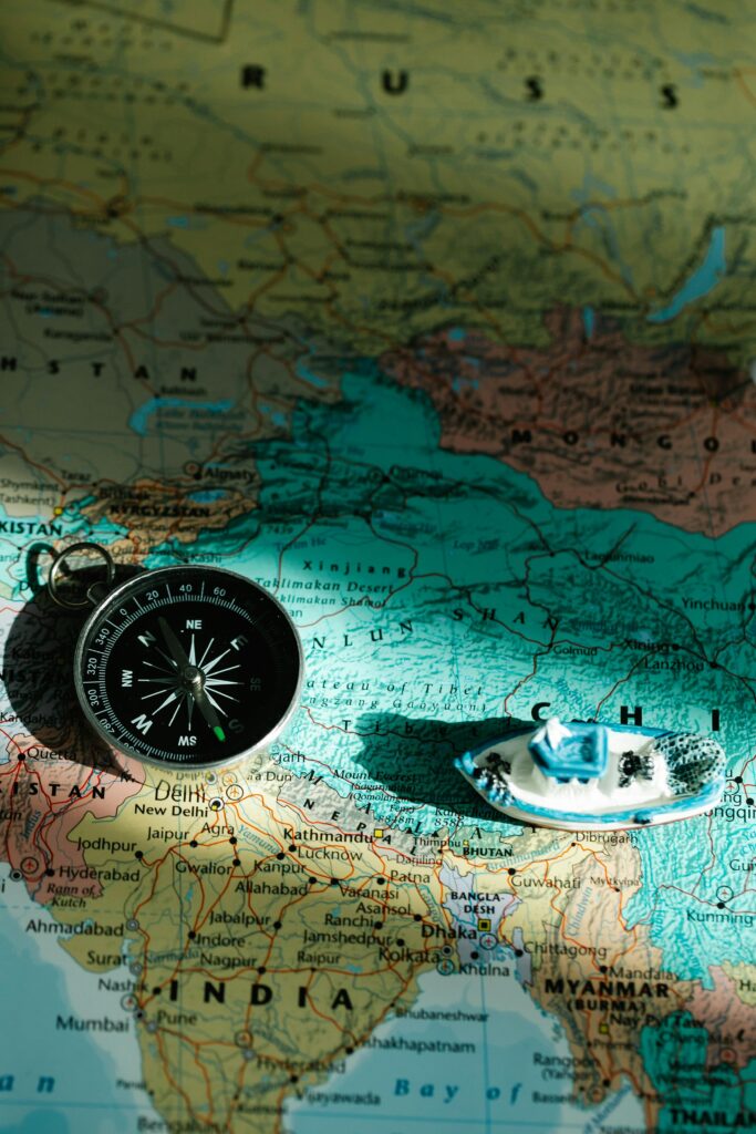 An overhead view of a map with a compass and toy boat symbolizing navigation and travel.